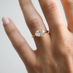 a woman's hand with a diamond ring on top of her finger, showing the center stone