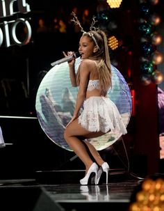 a woman in white dress on stage with microphone