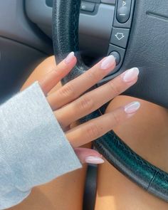 a woman's hand on the steering wheel of a car with pink and white nails