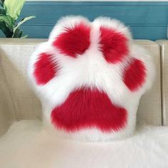 a red and white fur pillow sitting on top of a couch