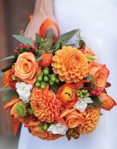 a bride holding an orange and white bouquet