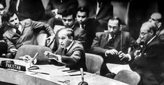 a group of men sitting at a table in front of a microphone