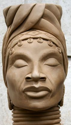 a clay sculpture of a woman's head with eyes closed