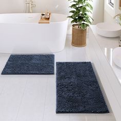 two bath mats sitting on top of a white floor next to a tub and sink