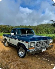 an old pickup truck parked in the dirt