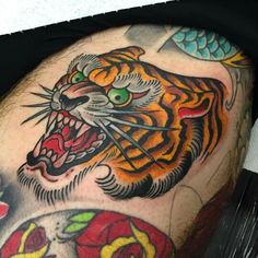 a man with a tiger tattoo on his thigh and chest is showing it's teeth