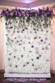 a white and purple backdrop with flowers on the wall for a wedding ceremony or reception