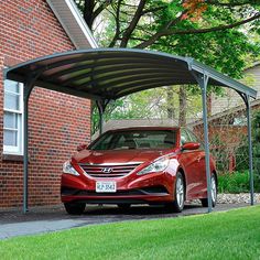 a red car parked in front of a brick building with a carport attached to it