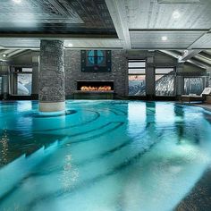 an indoor swimming pool with blue water in the middle and fireplaces on either side