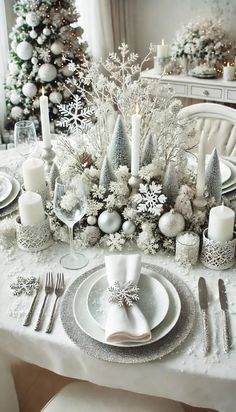 a table set for christmas with silver and white decorations