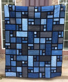 a blue and black quilt hanging on the side of a door with windows behind it