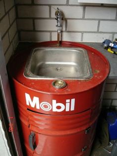 a red metal sink sitting next to a brick wall