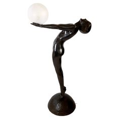 a black statue holding a white ball on top of it