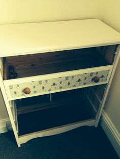 a white cabinet with drawers in a corner next to a wall and carpeted floor