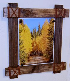 a wooden frame hanging on the side of a wall next to a tree filled forest