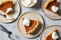 three plates with slices of pumpkin pie on them and one slice has whipped cream on top