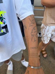 a man with a tattoo on his arm and foot is standing next to another person