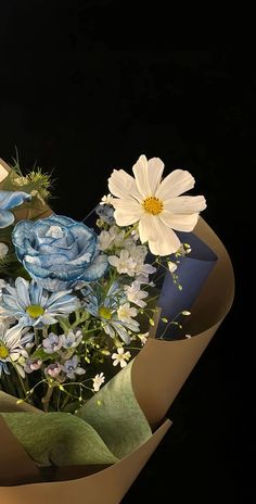 a bouquet of flowers sitting in a vase on top of a black surface with white and blue flowers