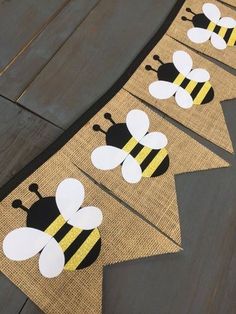 three bees on burlap banner with black and yellow stripes, sitting on a wooden floor