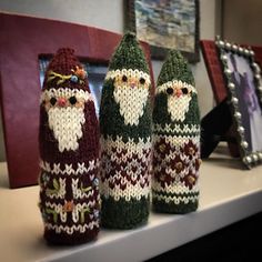 three knitted santas sitting on top of a shelf