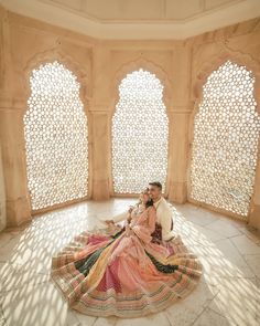 a man and woman are sitting on the floor in an ornate room with arched windows