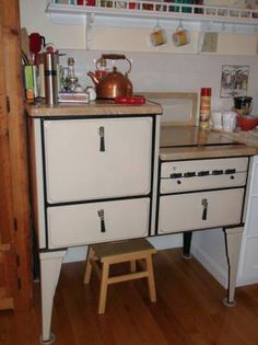 an old fashioned kitchen with wooden floors and white cabinets, including a stove top oven