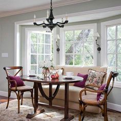 a living room filled with furniture and a chandelier hanging from the ceiling over a table