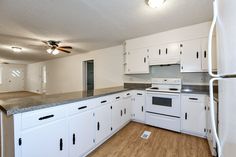 an empty kitchen with white cabinets and appliances