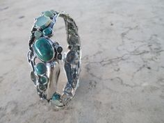 From Porans collection: Sterling Silver Bracelet with 28 stones inlaid. Turquoise, Labradorite, Green quartz, opalite & Aventurine. The bracelet can be ordered with a combination of stones. Please check with me what options are available Dimensions: Max Width: 20 mm bangle size- 63 mm Please let me know if you have any questions. our jewelry shop on Etsy: http://www.etsy.com/shop/Porans Thank you for visiting our shop. Please visit my shop policies for additional information Unique Chrysocolla Bracelets As Gifts, Handmade Green Sterling Silver Bangle, Green Bracelet With Stone Setting As Gift, Green Bangle With Natural Stones For Gift, Unique Green Gemstone Bracelets, Unique Cabochon Bangle Bracelets, Spiritual Green Bangle Cuff Bracelet, Green Bangle Bracelets In Fusion Style, Green Gemstone Bangle Cuff Bracelet