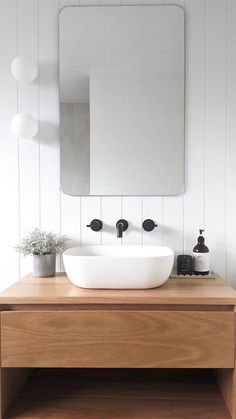 a white sink sitting on top of a wooden counter next to a mirror and light fixture