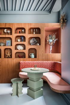 a table and bench in a room with shelves on the wall behind it, along with other furniture