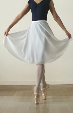 a woman in a white and blue dress is standing on the floor with her hands behind her back