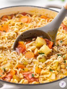 a pot filled with pasta and vegetables being stirred by a ladle