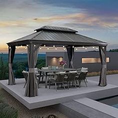 a gazebo sitting on top of a patio next to a swimming pool at dusk