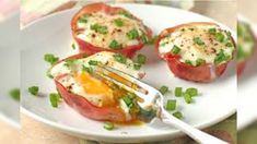 an egg and tomato dish on a white plate with a fork in the middle, ready to be eaten