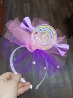 a person holding a lollipop in their hand with a purple bow on it