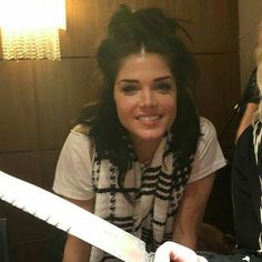 a woman holding a knife in her right hand while sitting next to another woman with long hair