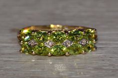 The Clayton: Stackable Peridot and Diamond Band in Yellow Gold. The ring features two rows of oval brilliant cut natural peridot set east to west across the center with four diamond-shaped sections set with natural round diamonds. Low set and well made,the ring is very comfortable to wear and the peridot are outstandingly matched to perfection. The ring is crafted in 14 karat yellow gold and is currently a finger size 7 3/4 yet can be adjusted to any finger size for an additional charge on reque Knot Ring, Diamond Shaped, Diamond Band, Rose Cut Diamond, Diamond Bands, Rings Statement, Diamond Shapes, Round Diamonds, Statement Rings