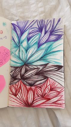 an open notebook with colorful drawings on the pages and in front of it is a pink flower