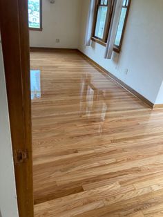 an empty room with hard wood floors and windows