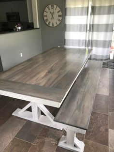 a large wooden table sitting in the middle of a room with a clock on the wall