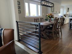 a dining room table and chairs in front of an open kitchen area with wood flooring