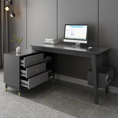 a computer desk with drawers and a monitor on it's side, in front of a gray wall