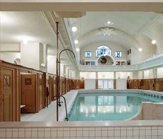 an indoor swimming pool in a large building with tiled floors and walls, surrounded by wooden lockers