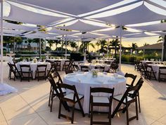 an outdoor dining area with tables and chairs set up for a formal function at sunset