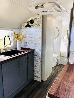 the interior of a camper with wood counter tops and blue cabinets, including a sink