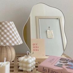 a table topped with books and candles next to a mirror on top of a shelf