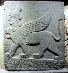 an ancient stone carving depicting a winged lion with a dog on it's back