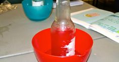 an empty bottle in a red bowl on a table