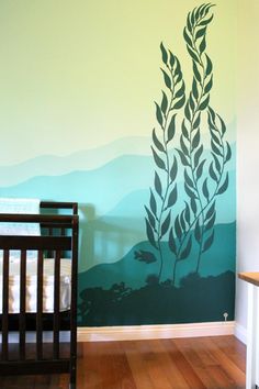 a baby's room with a crib and wall mural in the shape of seaweed